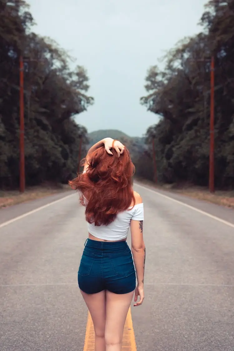 foto tumblr de menina ruiva, de costas, segurando o cabelo no meio da rua