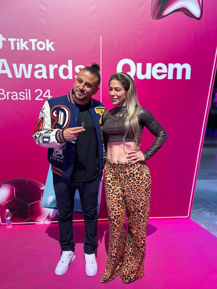 Patricio de roupa preta abraçado com sua esposa de cropped marrom e calça animal print no TikTok Awards 