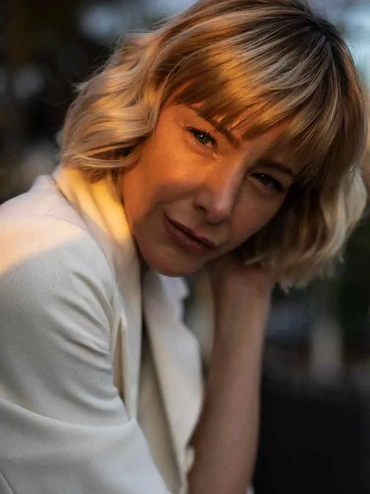 Mulher não-modelo com mais de 30 anos em ensaio fotográfico, usando blazer e sombra de maquiagem neutra