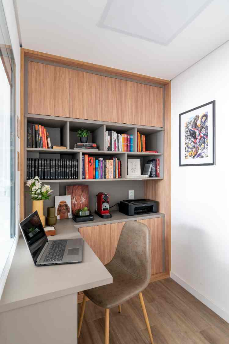 cantinho de leitura com parede de estante de livros e escrivaninha branca ao lado