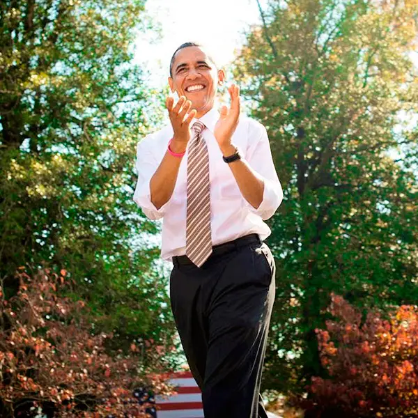 Barack Obama aparece de gravata, aplaudindo, com fundo de árvores em um dia de sol famosos do signo de leão: Barack Obama