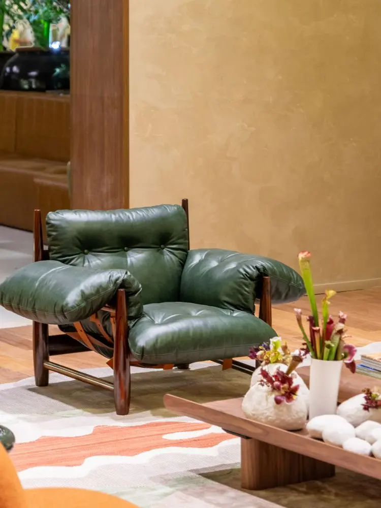 Sala em bege com poltrona verde, tapete em tons pastéis e mesa de centro de madeira com plantas