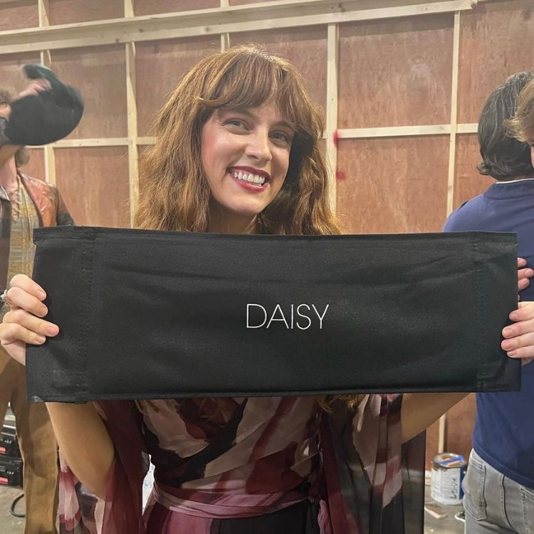 atriz riley keough segurando objeto com o nome de sua personagem escrito, daisy. 