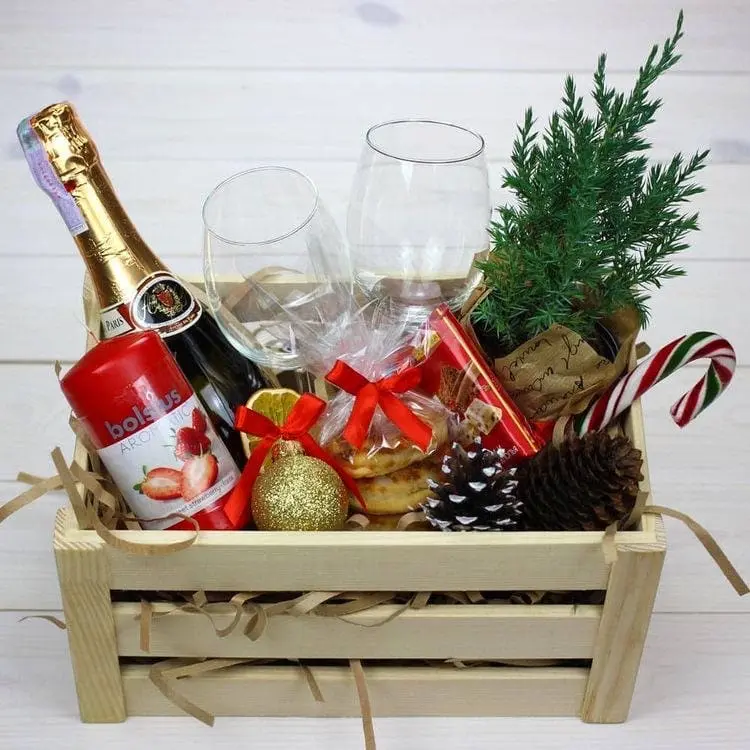 Cesta de Natal com vasinho de planta, taças, champanhe e pães 