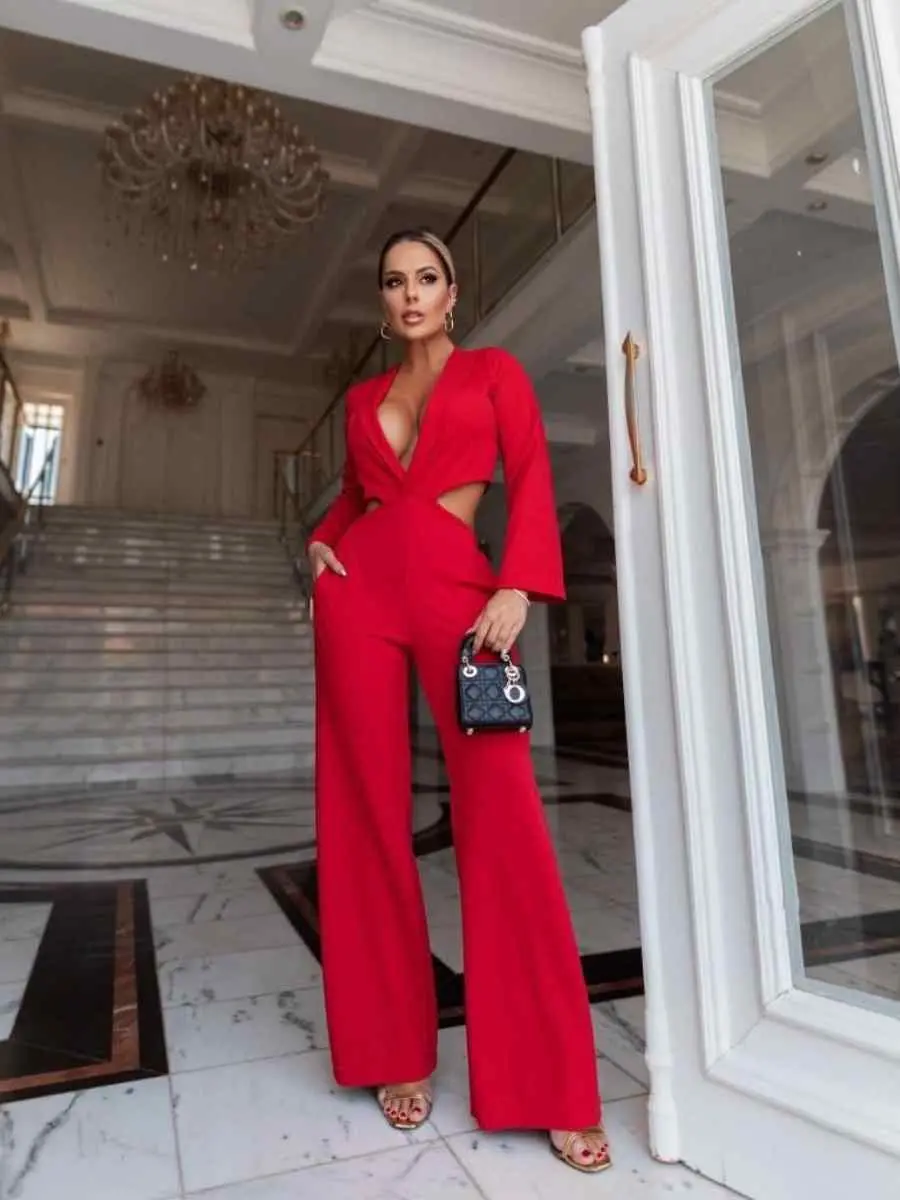 Mulher usando look vermelho para o Natal composto por macacão com recortes na cintura e grande decote