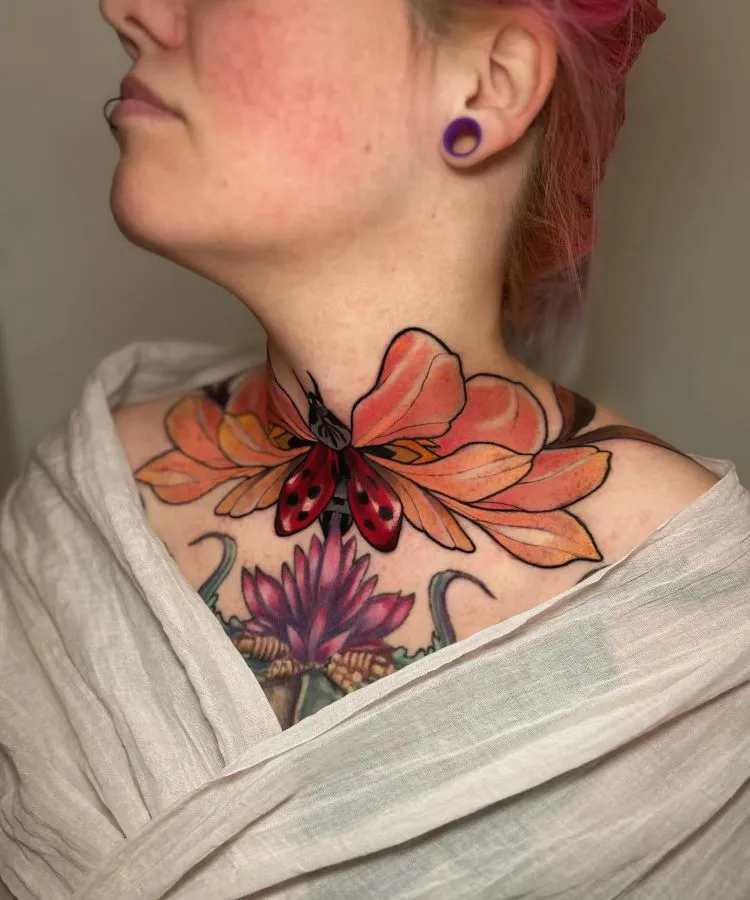 A imagem mostra uma pessoa de perfil com cabelo rosa preso em um coque. Ela tem uma tatuagem no pescoço de uma borboleta ou joaninha vermelha e preta, cercada por grandes pétalas de flor laranja. A tatuagem se estende até o peito, onde há uma flor de lótus roxa.




