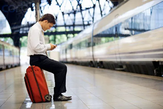 Businessman on Train Platform Text Messaging --- Image by © Randy Faris/Corbis