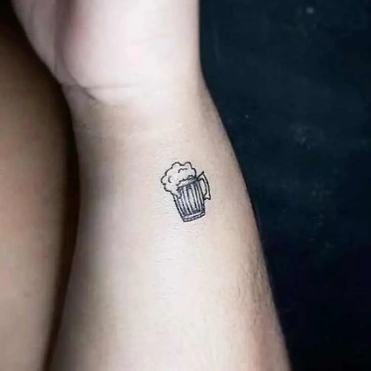 tatuagem de caneca de chopp na lateral do pulso