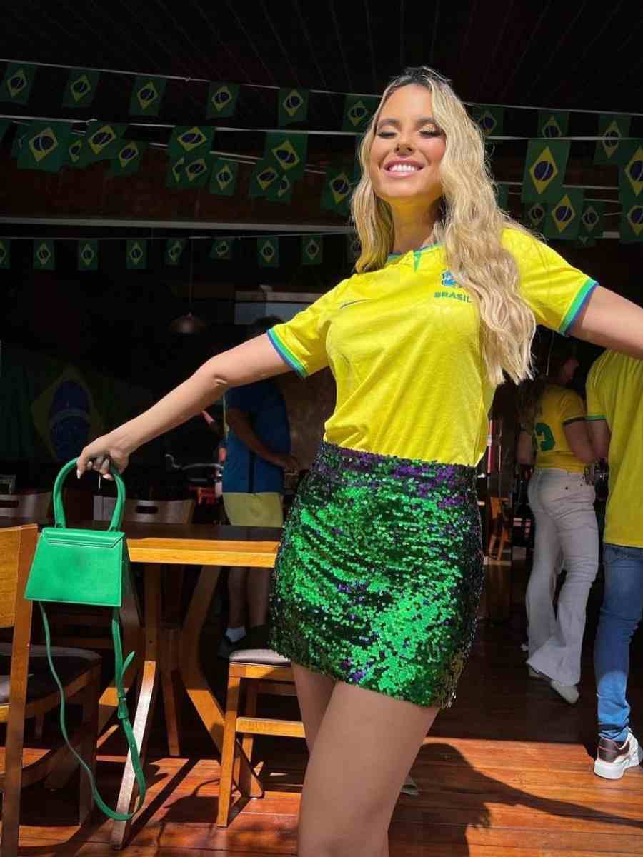 Foto de mulher usando camisa amarela do Brasil + saia verde de paetês e bolsa verde.