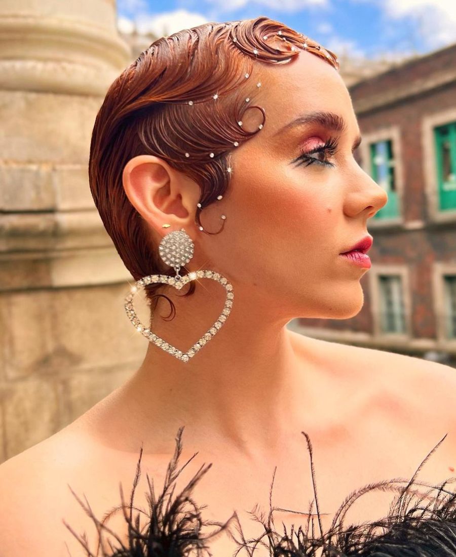 Mulher de pele clara com cabelo ruivo bem curto, com estilo "finger waves" (ondas marcadas) e strass