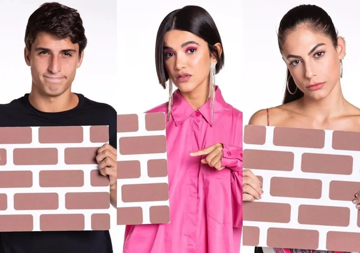 Imagem de três participantes do Big Brother Brasil segurando placas de parede de tijolos, simbolizando o paredão e a votação de eliminação no reality show