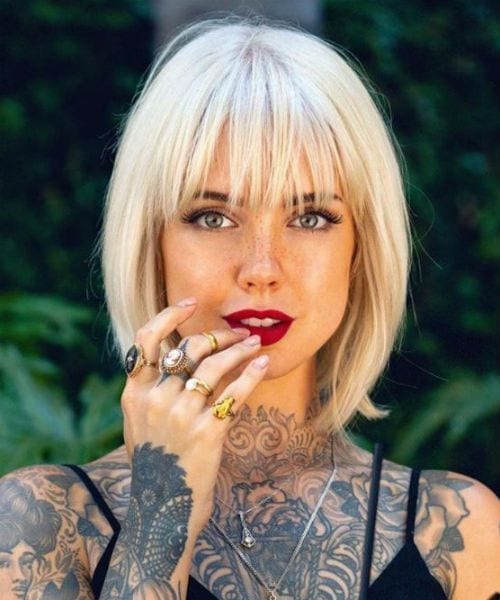 Mulher tatuada com Cabelo médio com franja platinado