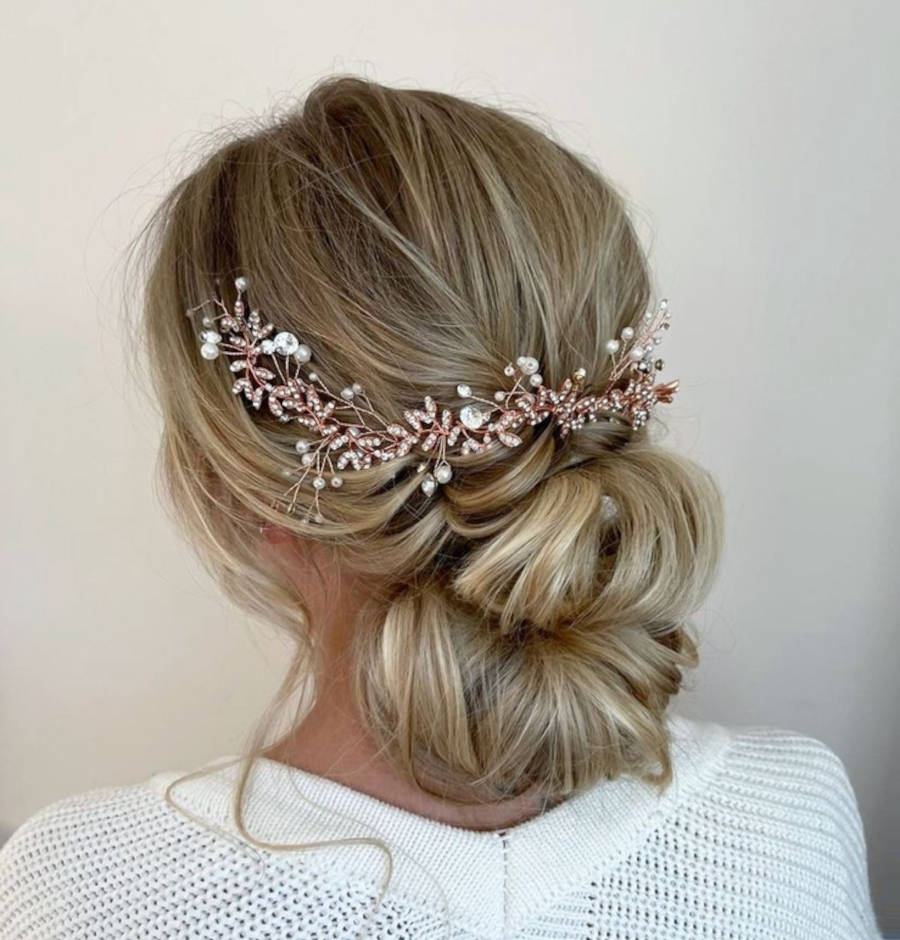Mulher de pele clara de costas usando coque com tiara de pedras e pérolas