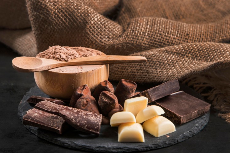 Tábua com chocolate em pó, trufas, chocolates amargos, chocolates brancos