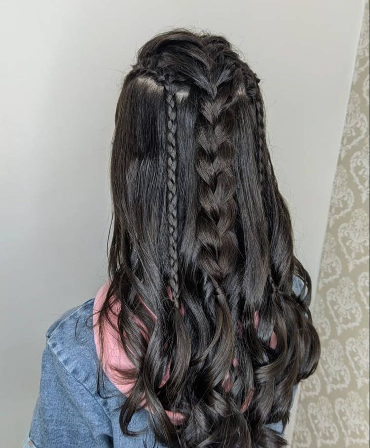 Mulher de costas com cabelo preto solto com trança grossa ao meio e uma fina de cada lado