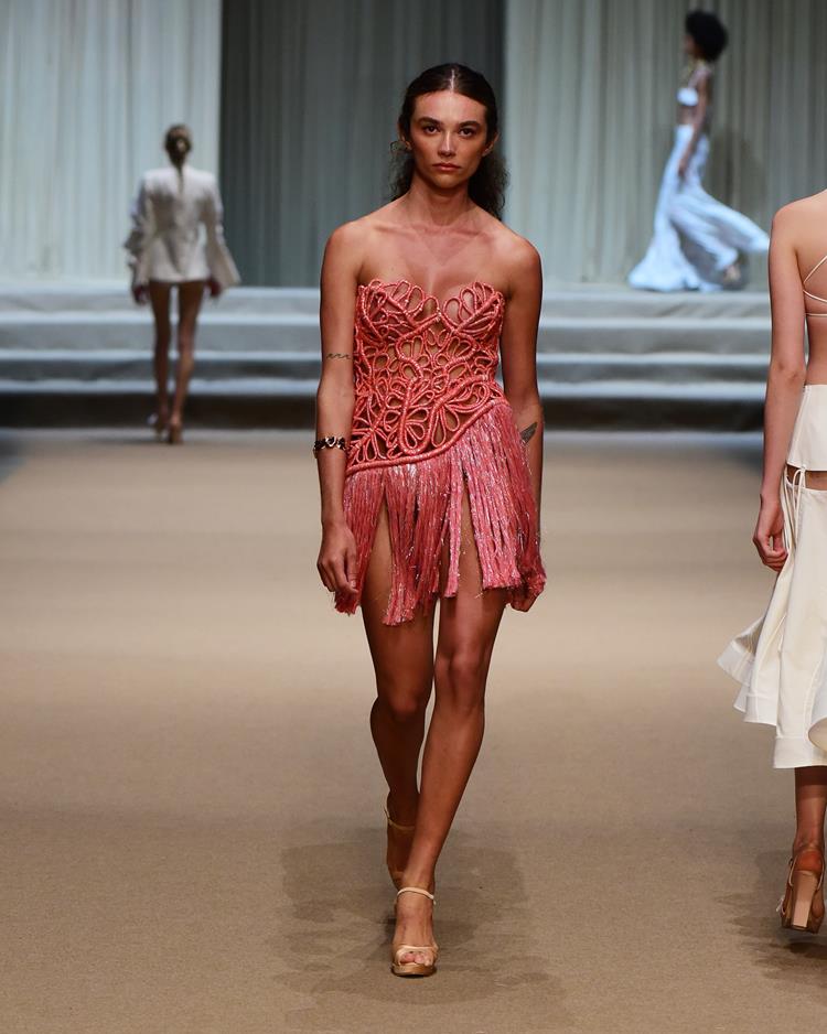 modelo com vestido curto rosa com bordado e franja.