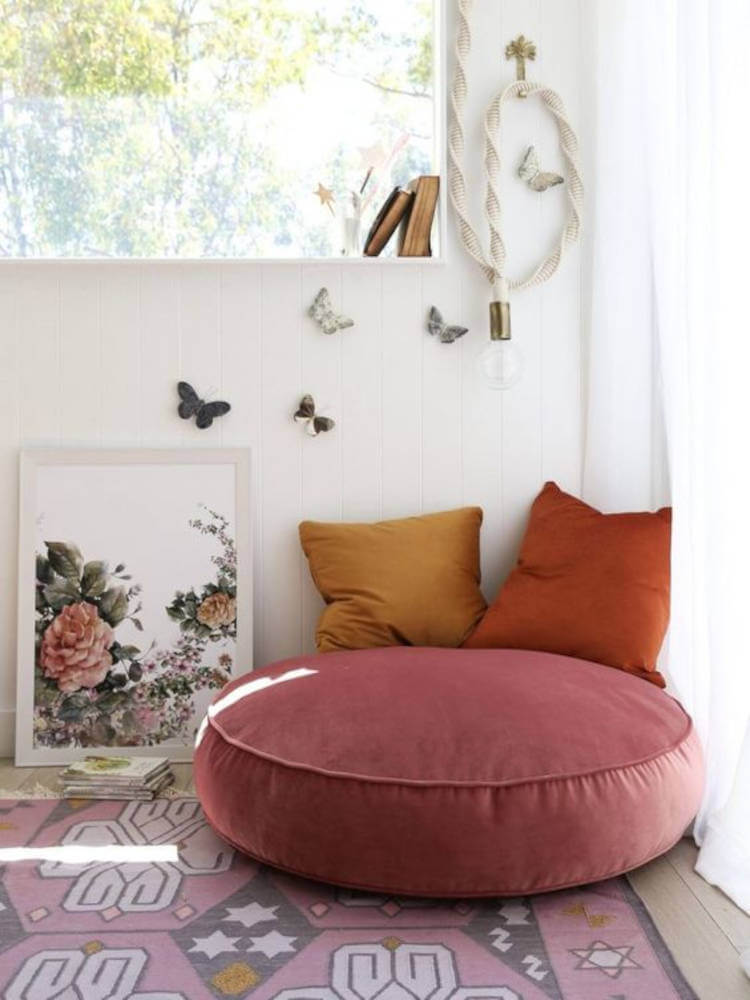 Decoração de espaço relaxante com borboletas 3d, quadro colorido, almofadas em tons terrosos, puff redondo rosa antigo e tapete rosa antigo 