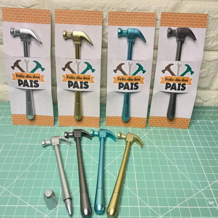 A primeira imagem exibe quatro canetas em formato de martelo, nas cores prata, dourado, azul e preto, cada uma apresentada em uma embalagem com a mensagem "Feliz dia dos PAIS". Abaixo, as canetas estão dispostas lado a lado, sem as embalagens.

