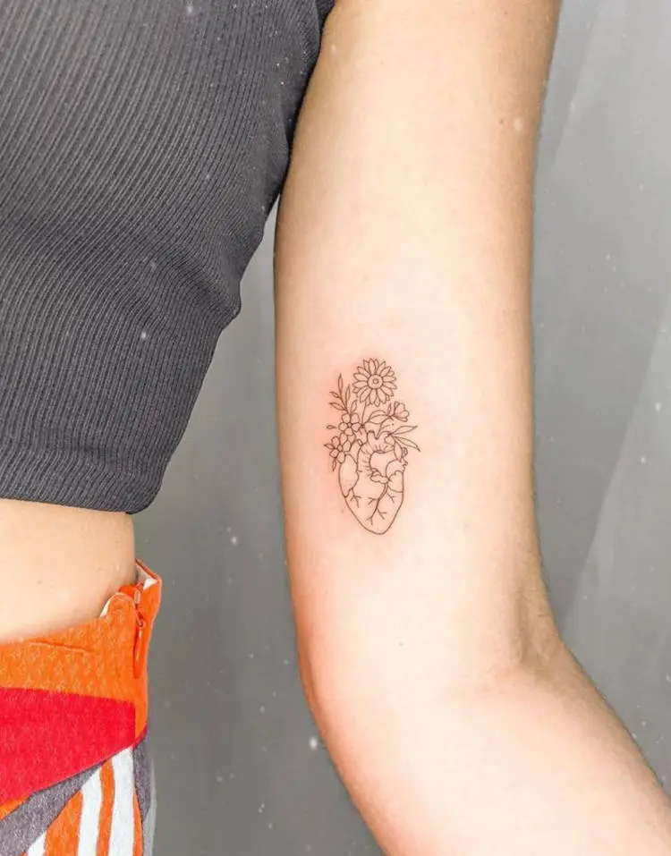 Tatuagem delicada de coração anatômico com flores