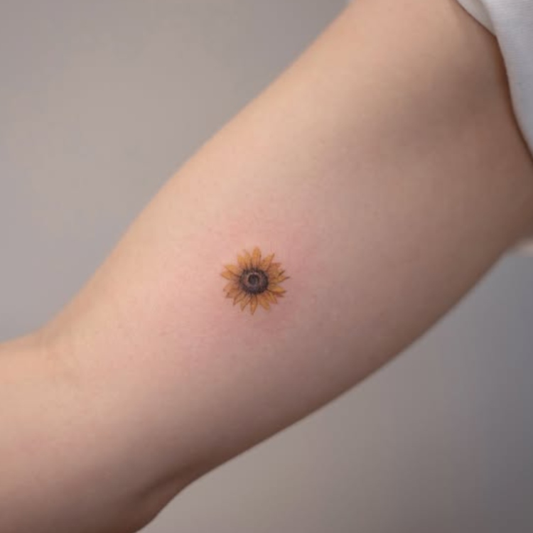 Tatuagem pequena, realista, colorida, de girassol no braço 