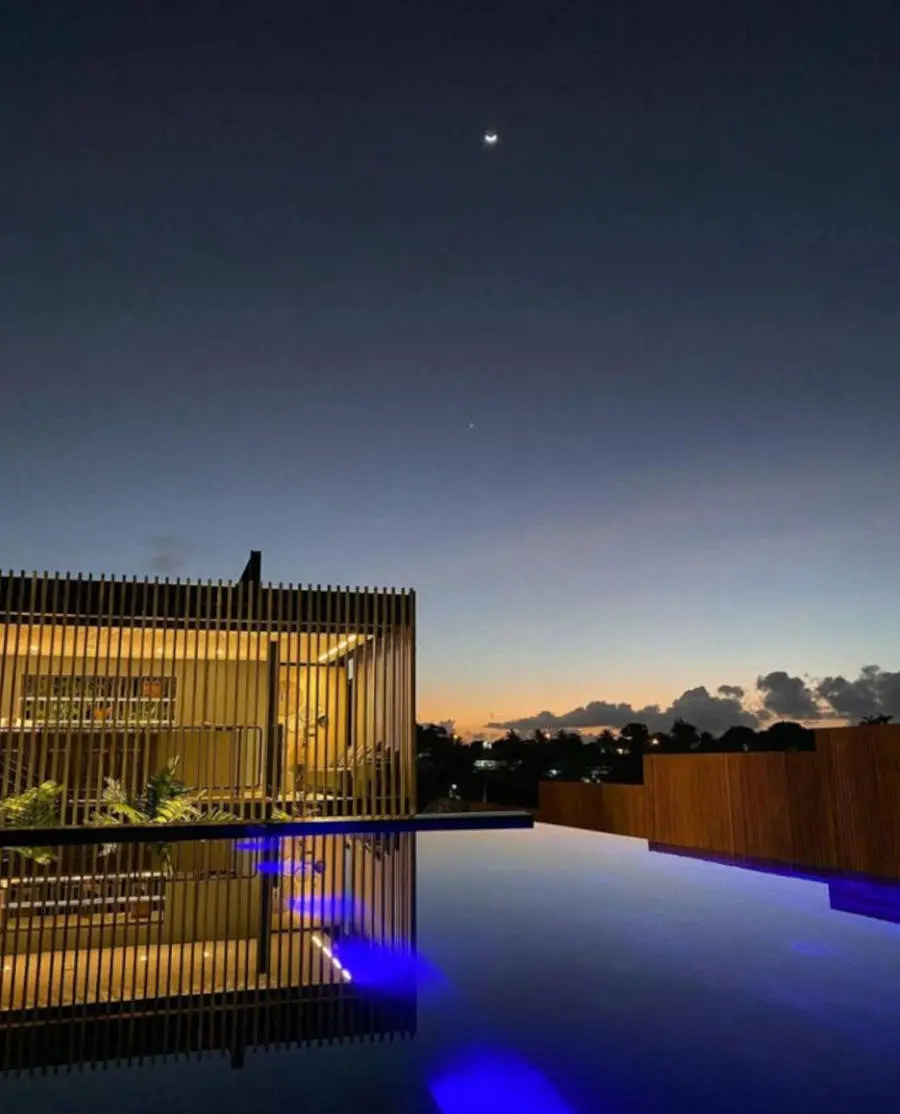 Foto a noite da fachada da pousada Maria Flor, com piscina de borda infinita
