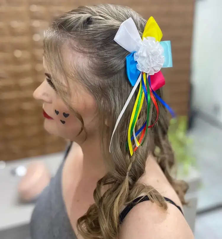 Laço colorido com flor branca no centro e fitas coloridas em cabelo castanho claro