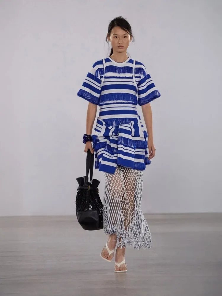 Foto de modelo na passarela da NYFW usando kimono listrado e saia branca de redinha da SIMKHAI