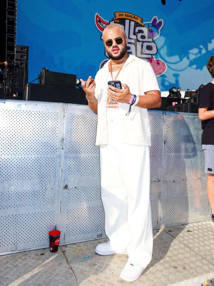 Lucas Guedes no Lollapalooza usando look all branco, com calça larga, regata, camisa e tênis