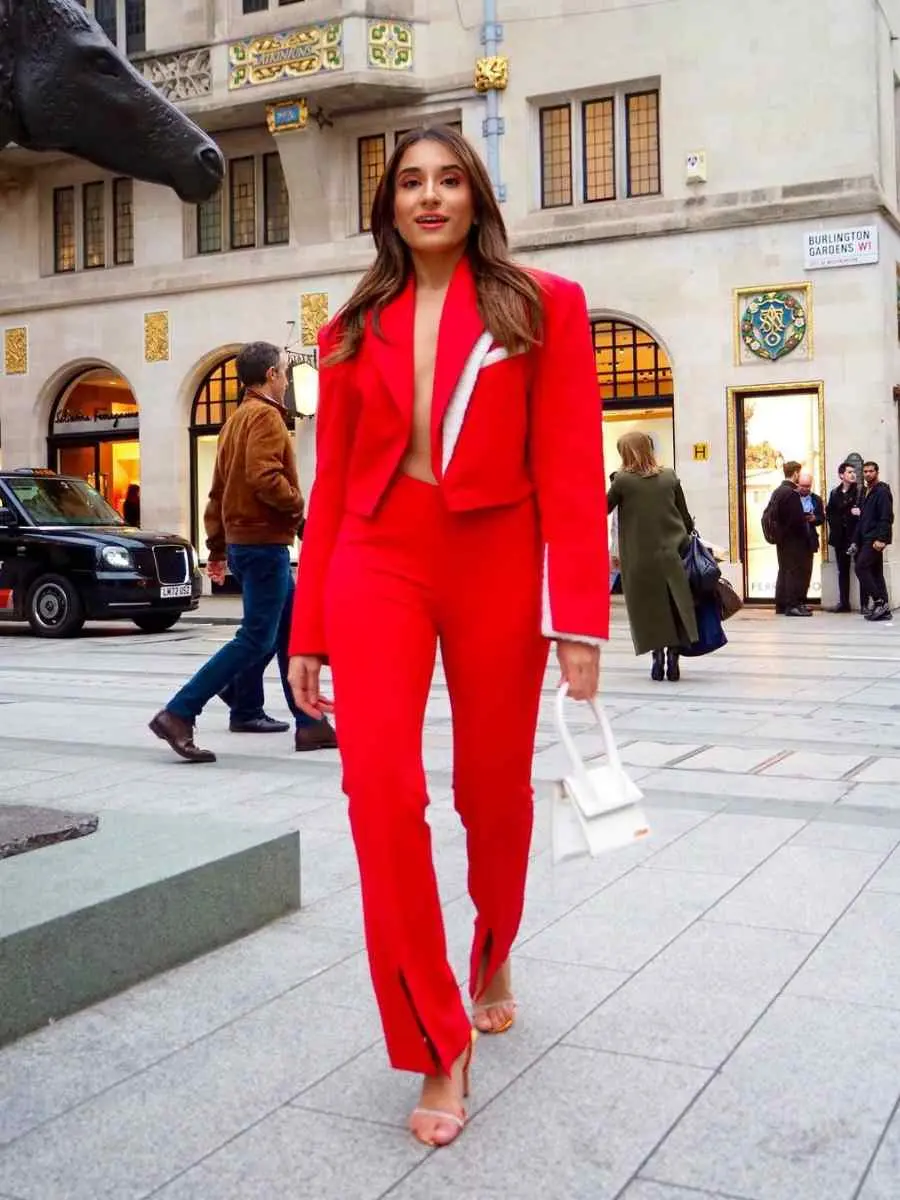 Mulher de pele clara andando na rua, usando look all red composto por blazer e calça.
