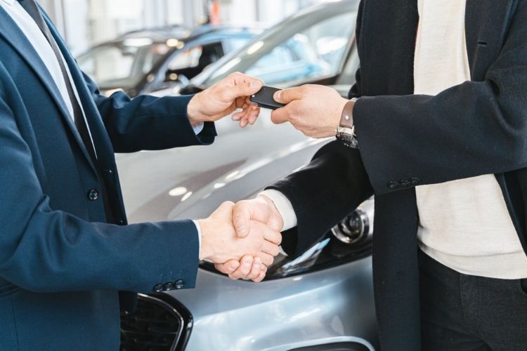 Comprador e vendedor de carro fechando negócio com a entrega da chave. Aperto de mão. carro rentável