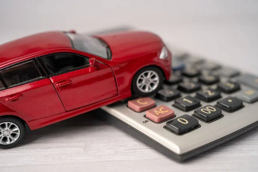 Imagem de carro vermelho de brinquedo em cima de uma calculadora