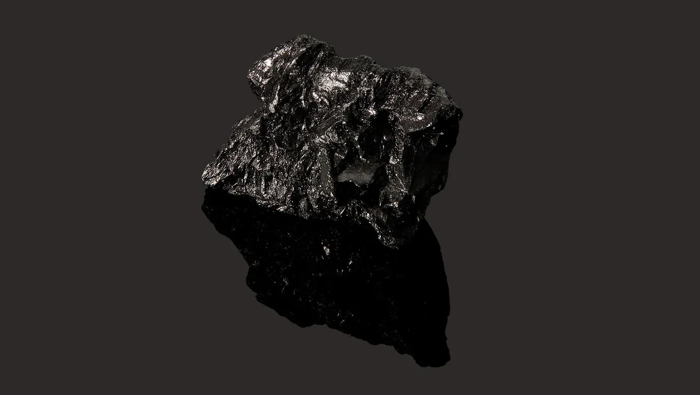 grafeno na moda Pedra preta, brilhante e irregular, que parece uma gema ou um mineral. A rocha é fotografada contra um fundo preto, e sua superfície áspera reflete a luz.

