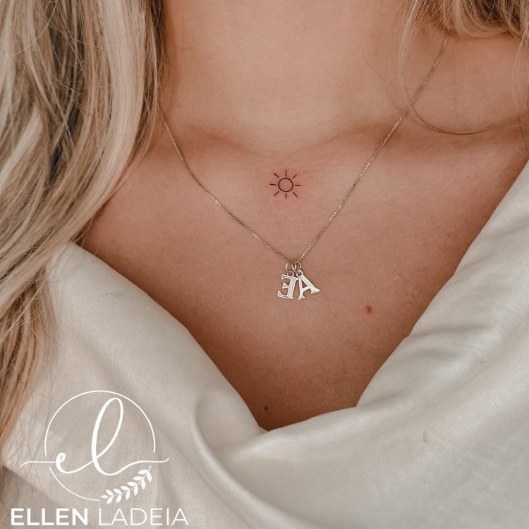 Tatuagem pequena de sol em fineline entre as clavículas 