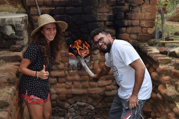 Influenciadora Júlia Tolezano ao lado de homem em um tipo de forno rústico