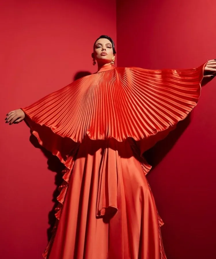 Foto de mudelo usando vestido vermelho com capa plissada da marca Vitor Zerbinato
