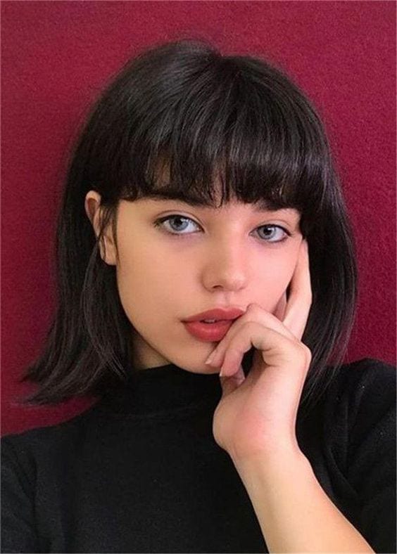 Menina de cabelo preto e olhos azuis com corte de cabelo feminino curto com franja