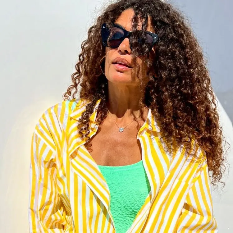 Mulher de óculos com regata verde e camisa de listras branco e amarelo