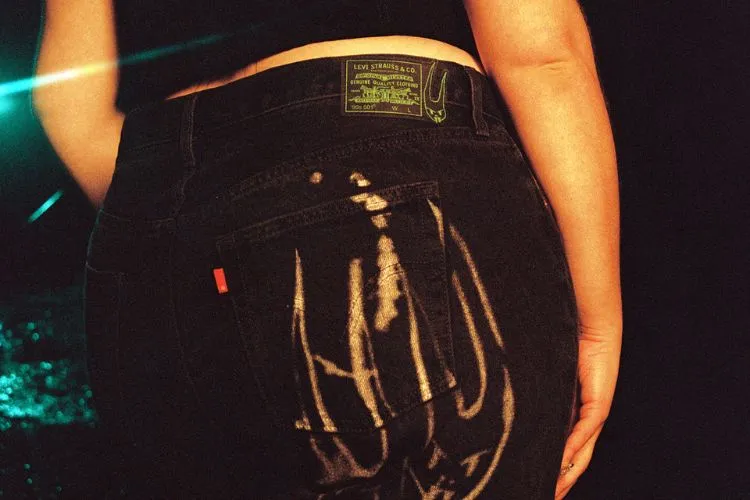 Um close-up na claça, uma calça preta com uma estampa cinza e uma etiqueta da Levis