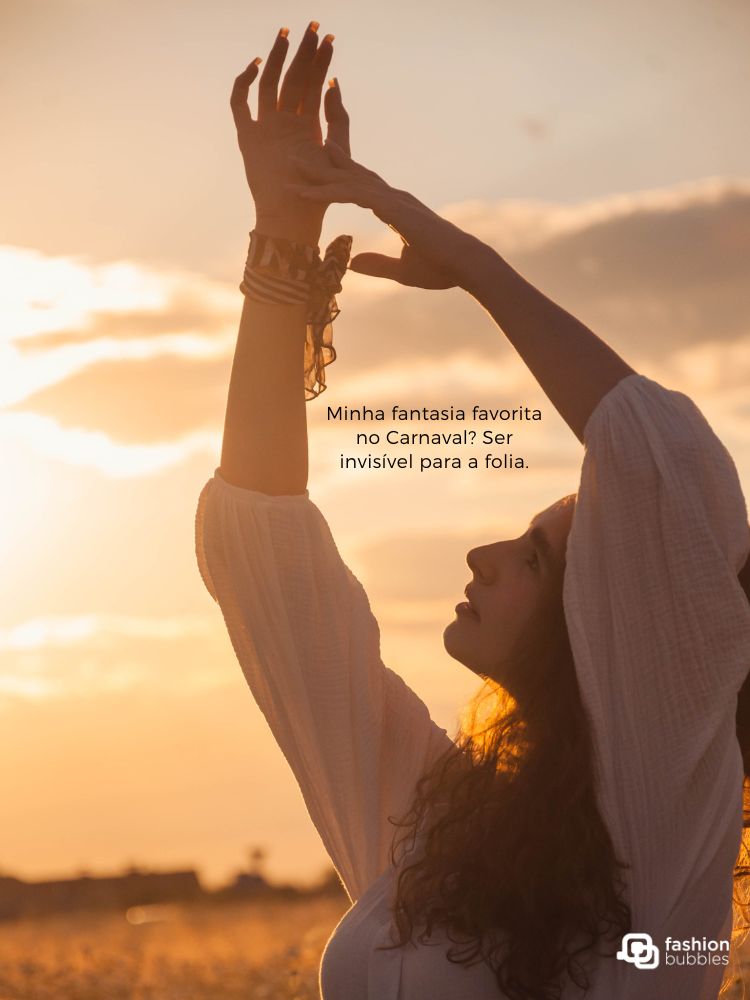 A imagem retrata uma mulher de perfil ao pôr do sol, com braços erguidos, transmitindo serenidade. Ela usa uma blusa leve e braceletes. A frase "Minha fantasia favorita no Carnaval? Ser invisível para a folia" está sobreposta à cena.