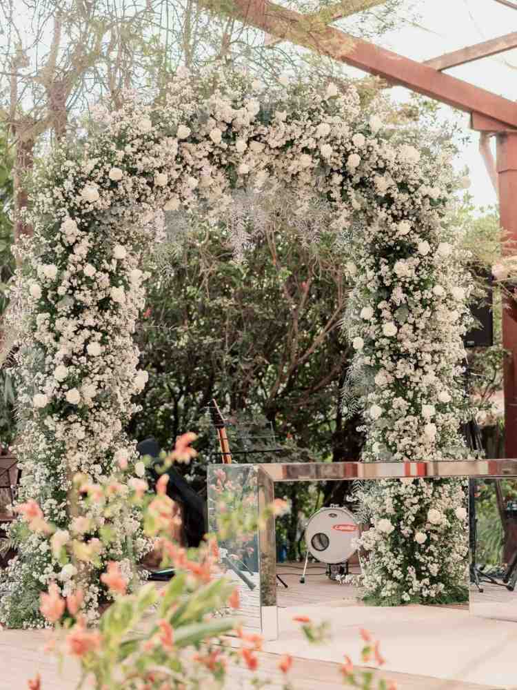 Altar de casamento maximalista com muitas flores brancas.