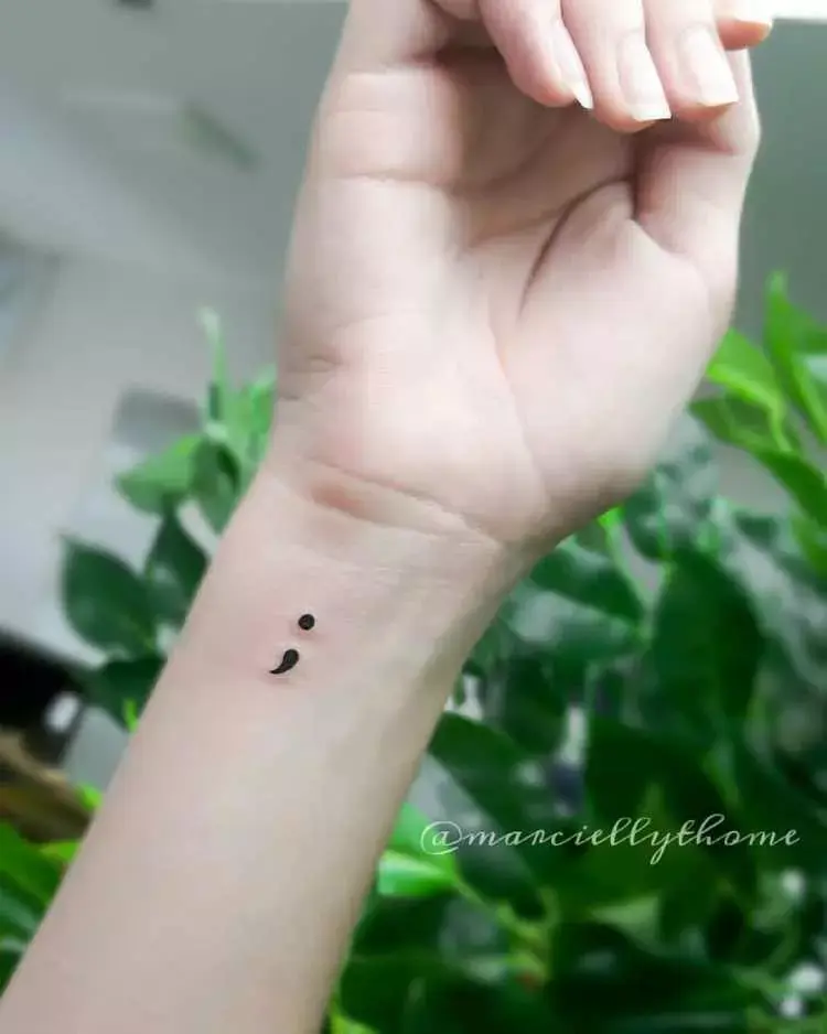 tatuagem na parte inferior do pulso de ponto e vírgula pintados de preto