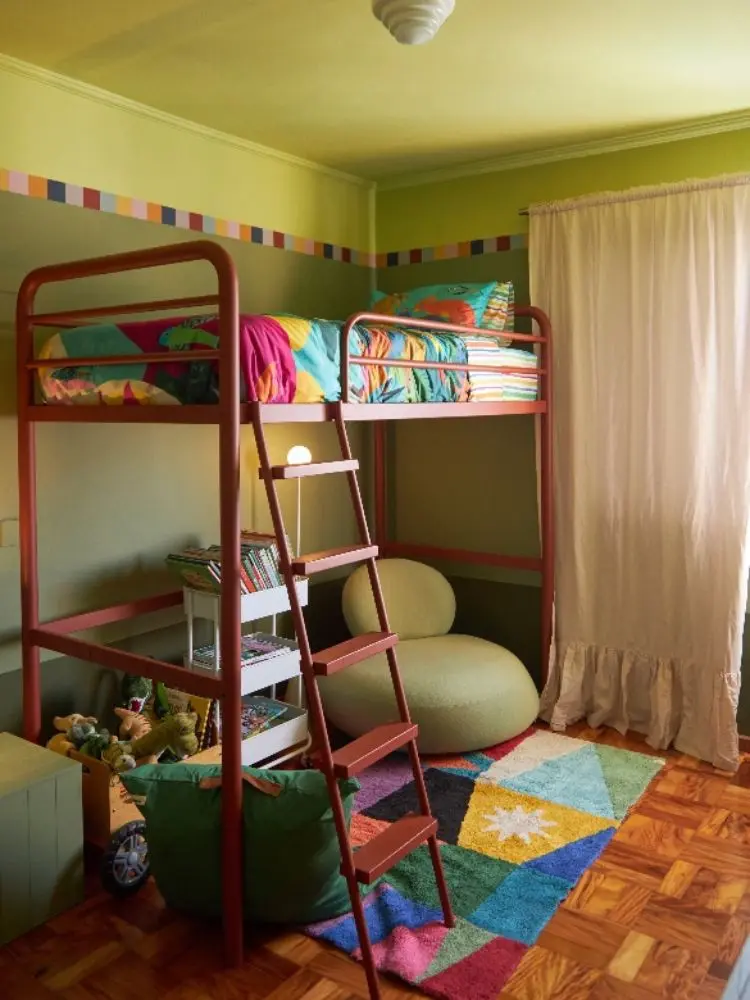 Quarto em verde com cama em cima, puff e tapete colorido 
