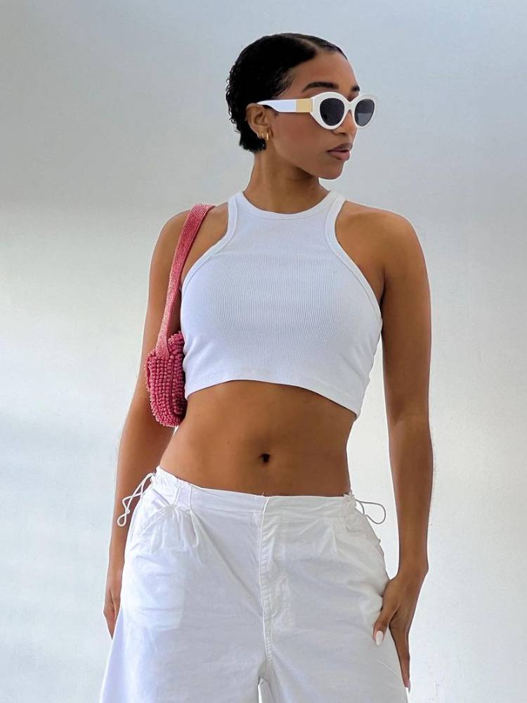 mulher usando cropped branco com calça parachute branca