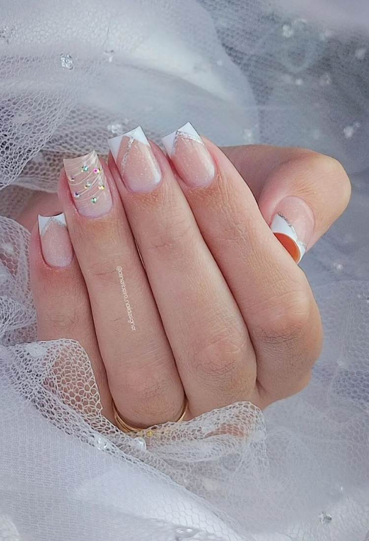 Unhas quadradas com gravatinha branca e efeito teia com pedras coloridas no anelar