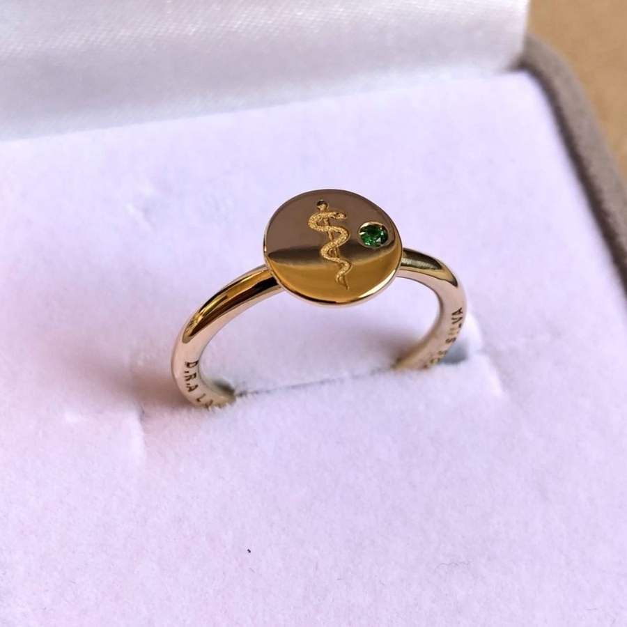 Anel de ouro com chapa, desenho símbolo de medicina e pedra verde