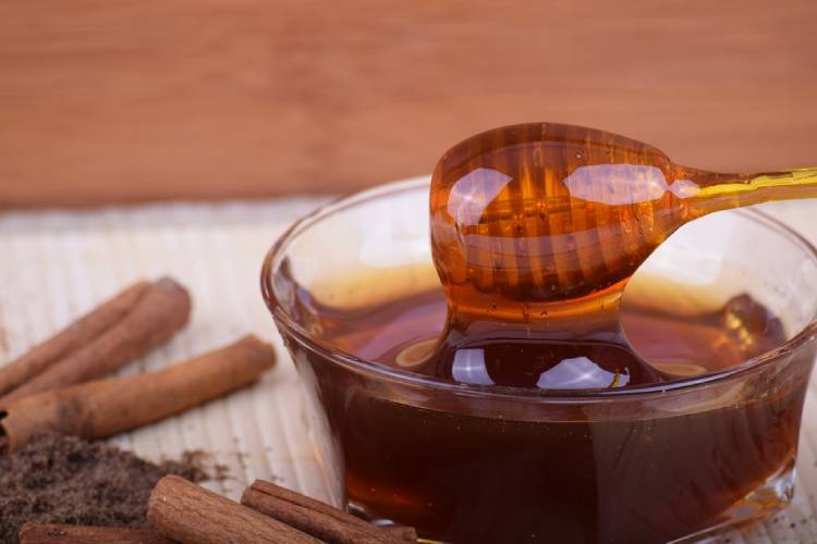 pote de vidro com mel ao lado de paus de canela foto de mel com canela benefícios
