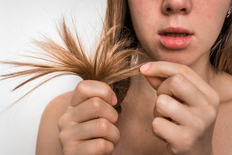 Mulher olhando as pontas de seu cabelo.