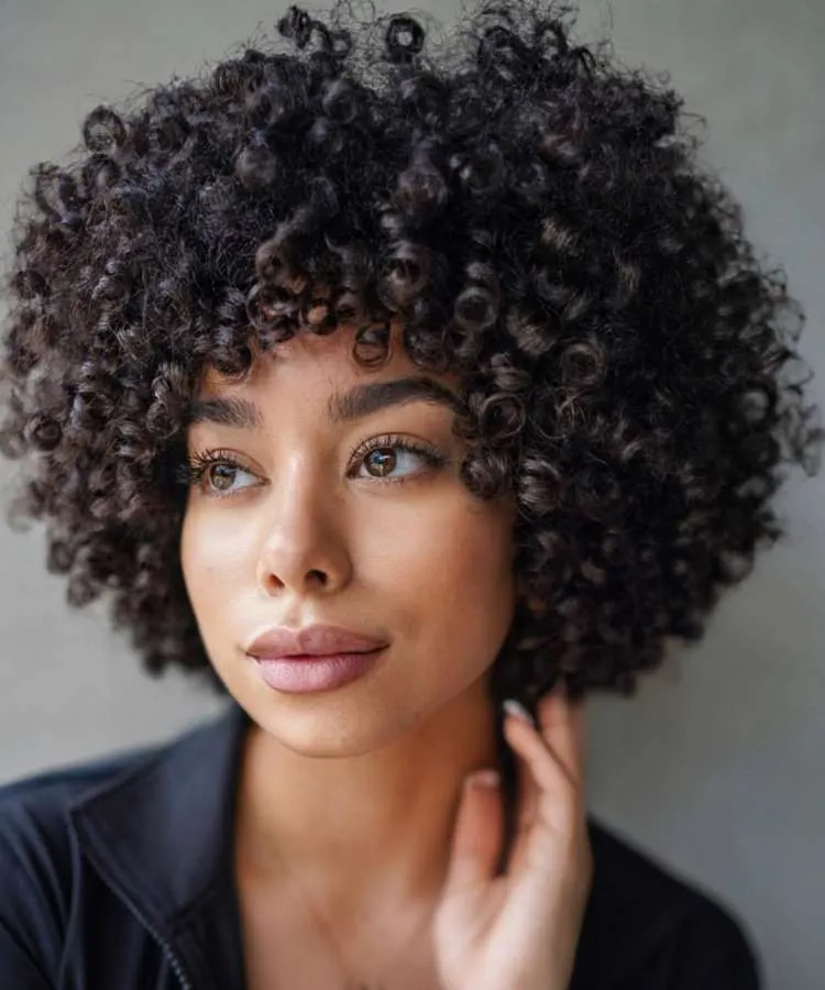 Mulher com cabelo crespo castanho curto e repicado