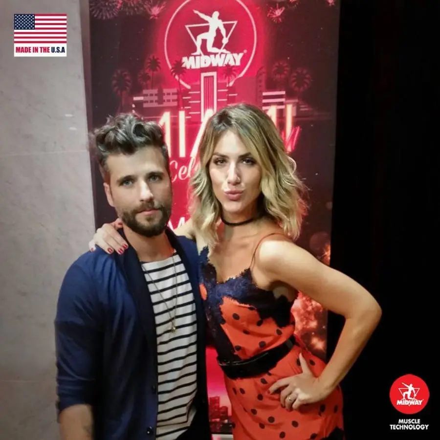 Bruno Gagliasso e Giovanna Ewbank em frente a um banner da Midway USA