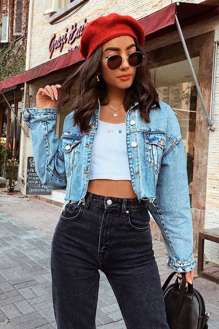 Mulher de pele clara usando cropped branco, jaqueta jeans cropped e calça lavagem escura